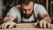 © Marketplace - Concentrated carpenter working diligently on a wooden project in a workshop, surrounded by tools and wood shavings, showcasing craftsmanship.