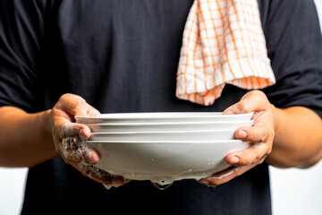 A man lifts a soapy plate he is washing, representing the concept of a husband doing household chores