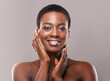 © Prostock-studio - Beautiful black woman with short hair touching her smooth cheeks, applying cream or lotion on face and looking at camera, copy space