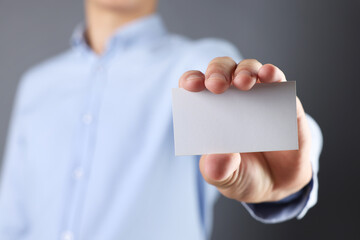 Wall Mural - man holding blank business card on grey background, closeup. mockup for design