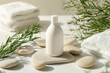 © Keopaserth - Minimalist white cosmetic shampoo dispenser bottle surrounded by soft towels, smooth stones, and fresh greenery, creating serene and calming atmosphere
