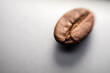 © athian - Close-up of a single, roasted coffee bean with its characteristic groove, against a bright background. Aromatic and essential for coffee.