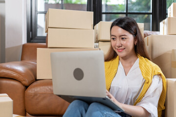 Young Asia woman typing talking to online customer and checking order process for drop shipping on laptop. SME small business owner happy for success self-employed working at home.