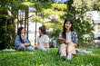 © bongkarn - Charming Asian female college student sits on the grass in her college campus park, holding a tablet
