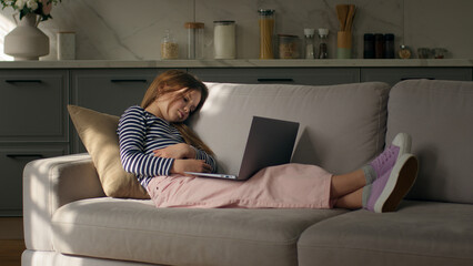 Little girl lying on sofa home cozy comfortable watching movie laptop comedy technology computer relax weekend enjoy child kid laughing device film pastime internet gadget video leisure funny female