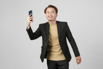 portrait of happy asian businessman wearing suit holding mobile phone on isolated background