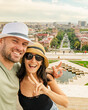 © Evaldas - Happy young caucasian couple take selfie pose for mobile photo. Visit Armenia capital enjoy Sightseeing Yerevan city landmarks. Cascade complex with cityscape panorama in sunny day. Armenia travel