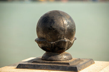 A black metal ball sits on top of a black metal base