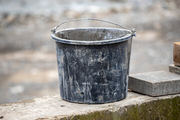 A dirty bucket sits on a cement wall