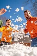 Un padre y su hijo disfrutan lanzando bolas de nieve bajo un cielo despejado. Ambos ríen y están vestidos con ropa de abrigo color naranja, destacando en el entorno nevado.