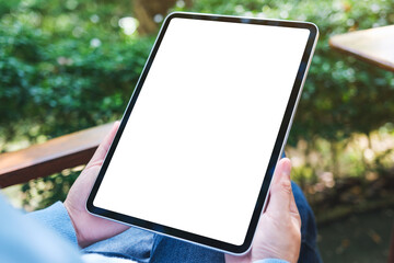 Mockup image of a woman holding digital tablet with blank white desktop screen in the outdoors