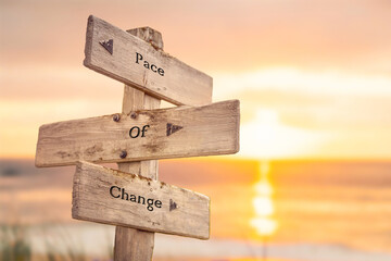 pace of change text quote written on wooden signpost by the sea during sunset and golden hour.