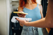 © standret - Worker is holding the terminal. Woman is paying for clothes, in the retail store