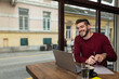 © Srdjan - One young businessman sitting in cafeteria taking a coffee break while working online on laptop computer. Business male professional occupation e-commerce and remotely finance and economy research