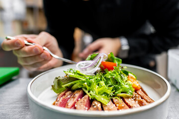 Wall Mural - A close-up of a fresh salad with sliced meat, garnished with onions and tomatoes, served on a white plate. The vibrant colors and textures highlight the freshness and appeal of the dish