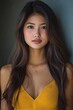© seksun - A very beautiful Thai woman with long, dark brown hair and hazel eyes, wearing a yellow top and necklace,