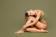 © ViDi Studio - Full body young nice happy calm lady woman with slim skinny body perfect skin wear top bra lingerie sits put head on knees look camera isolated on plain green background. Lifestyle diet fit concept.