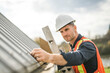 © Louis-Photo - man with hard hat standing on steps inspecting house roof