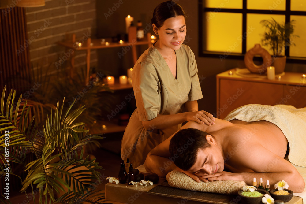 Female therapist massaging man in dark spa salon