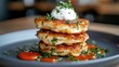 © JoxyAimages - Three gourmet potato pancakes garnished with sour cream and fresh herbs sit on a dark plate accompanied by sauce, offering a tempting culinary delight.