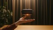 © rujlaphus - A black VR headset hovers above an outstretched hand in front of a brown curtain.