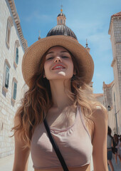 A woman wearing a straw hat and a tank top is smiling and posing for a photo