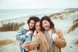 © Davor - Three young women friends taking a selfie on a windy beach