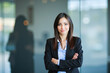 © Minerva Studio - Confident businesswoman smiling with folded arms in office building