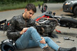 © Romario Ien - Motorcyclist sits on the asphalt near motorcycle, after road accidents with car. Broken and wrecked motorcycle on road