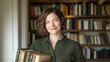 © OHMAl2T - Woman holding books in a cozy library setting
