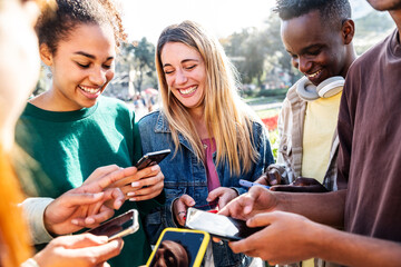 Happy group of multiracial teens using smart mobile phone outdoors - Diverse university students watching smartphones in college campus - Millenial people having fun on city street - Youth culture
