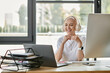 © Bliss - A young bald woman wears headphones, smiling while interacting on her laptop at a stylish desk.