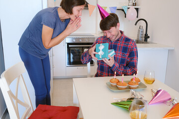 family exchanges gifts in dining room beautifully decorated for birthday celebration. the setting is