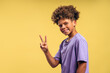 © Maria Vitkovska - Attractive, smiling, happy African American boy with curly hair showing peace sign looking at camera