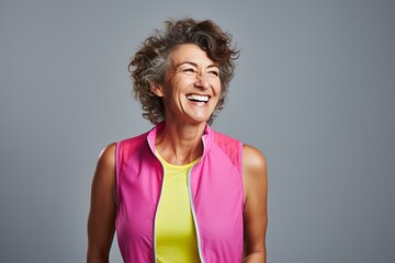 Canvas Print - Portrait of a joyful woman in her 50s wearing a lightweight running vest while standing against blank studio backdrop