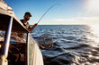 © Designpics - Man catches a fish from a boat during time on a lake; Alberta Beach, Alberta, Canada