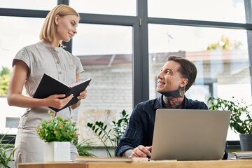 Two colleagues chat animatedly among vibrant plants in a bright workspace.