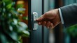 © JCreative - Elegant hand in a suit reaching for a polished metal door handle in a modern office setting