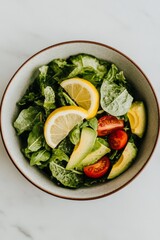 A bowl of salad with avocado, tomato and lemon wedges.