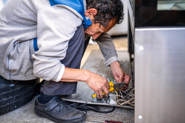 An adult man holds pliers in his hands for work.