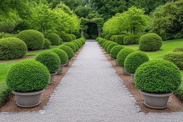 A gravel path lined with topiary bushes leads to a stone archway in a lush green garden.