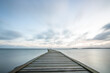© Jan - Sunrise over a lake in autumn. A wooden jetty protrudes into the water while grass has established itself on the sandy beach. The lake and beach, located on Lake Vänern in Näs Sannar, Sweden, Scandina