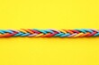 © New Africa - Braided colorful ropes on yellow background, top view. Unity concept