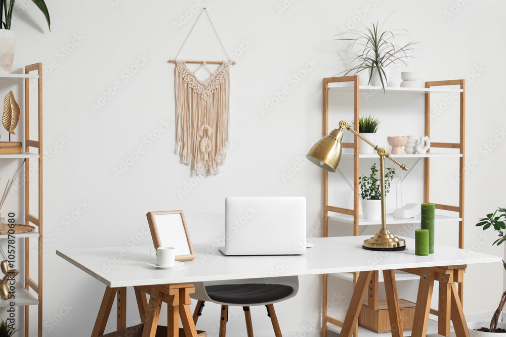 Interior of modern stylish workspace with shelving units and laptop on table