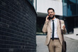 © Zamrznuti tonovi - Businessman walking and talking on the phone while holding coffee