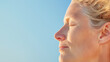 © Stacy - Gray-haired woman enjoying the sun with closed eyes and a peaceful expression against a blue sky
