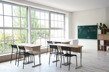 Wall Mural - Interior of empty classroom with school desks and text BACK TO SCHOOL on chalkboard