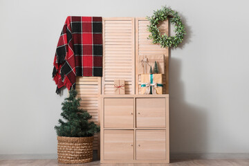 Chest of drawers, folding screen, Christmas decor and mistletoe wreath in interior of living room