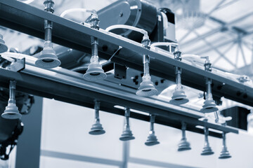 Poster - A robot is holding a machine with  handles. The robot is in a factory setting. The machine is being used to hold a part in place