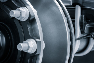 A close up of a wheel with a lot of bolts and nuts. The wheel is black and silver, industrial machinery concept background